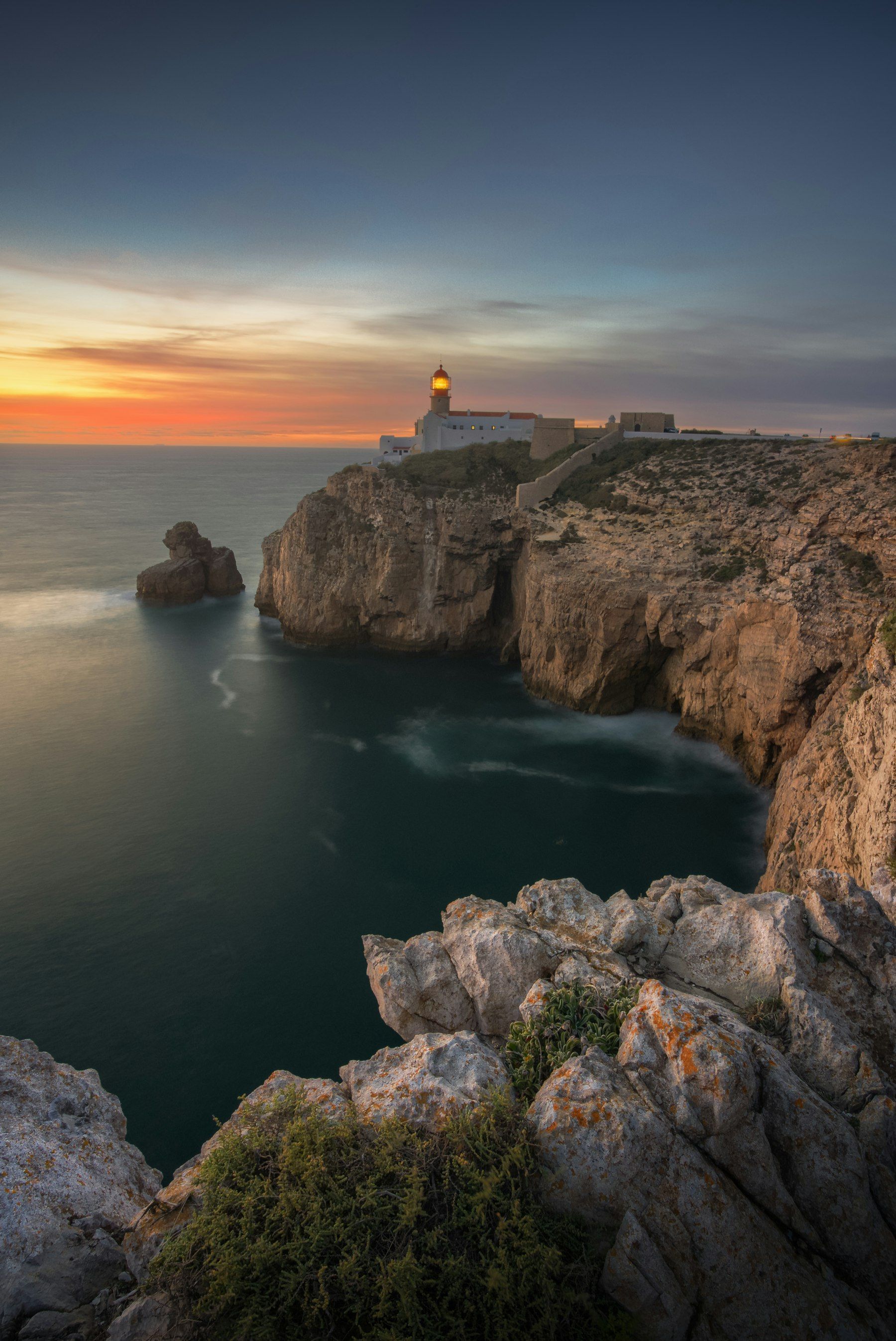 A lighthouse on a cliff at sunset